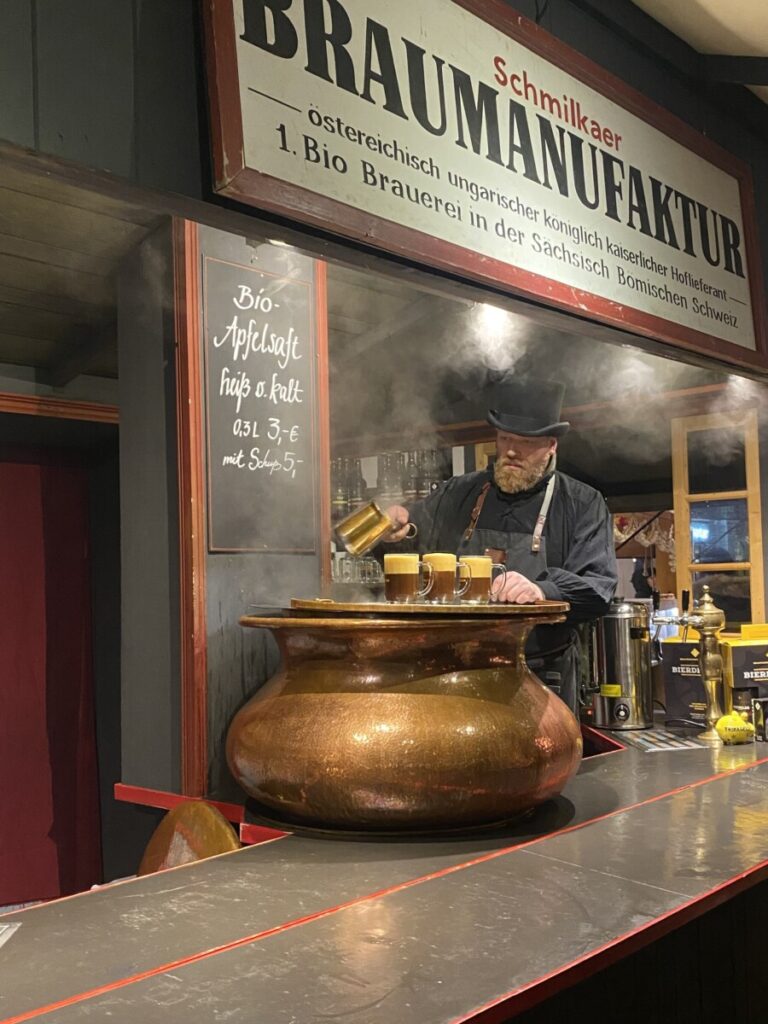 A cauldron at the Neumarkt Christmas Market and man pouring 3 glasses